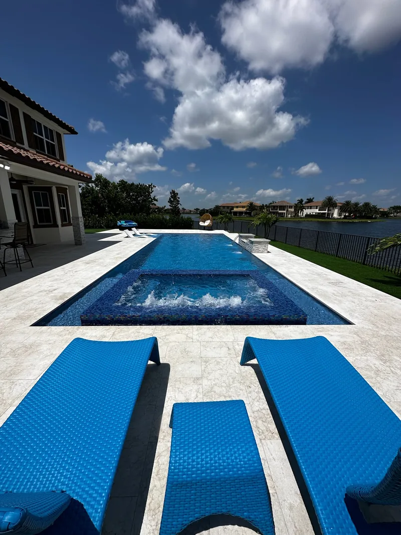 Blue loungers in the foreground with a pool and bubbling spa behind