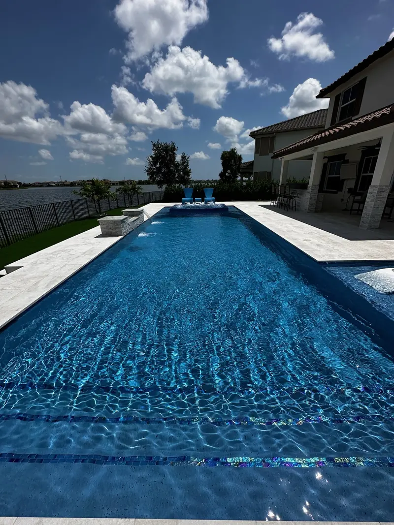 Rippling blue pool water with a tile line on the step and white loungers in the distance