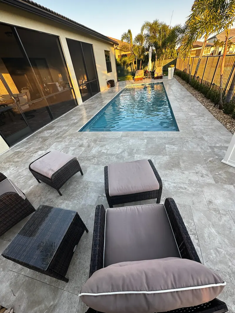 Lanai patio with cushioned chairs overlooking a small pool on stone-style pavers