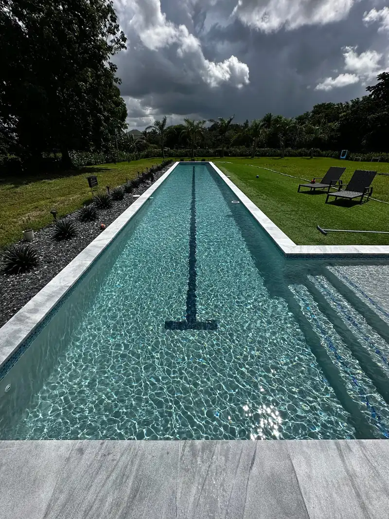 Lap pool with a dark lane line, clear rippling water and gray paver steps