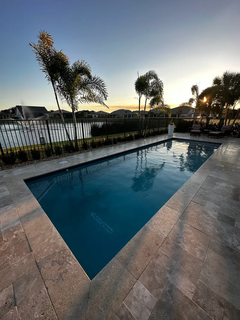 Pool with deep blue water reflecting palms beside a lake at dusk