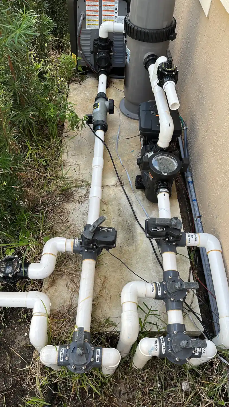Pool equipment pad with two pumps, a filter and white PVC plumbing with three-way valves