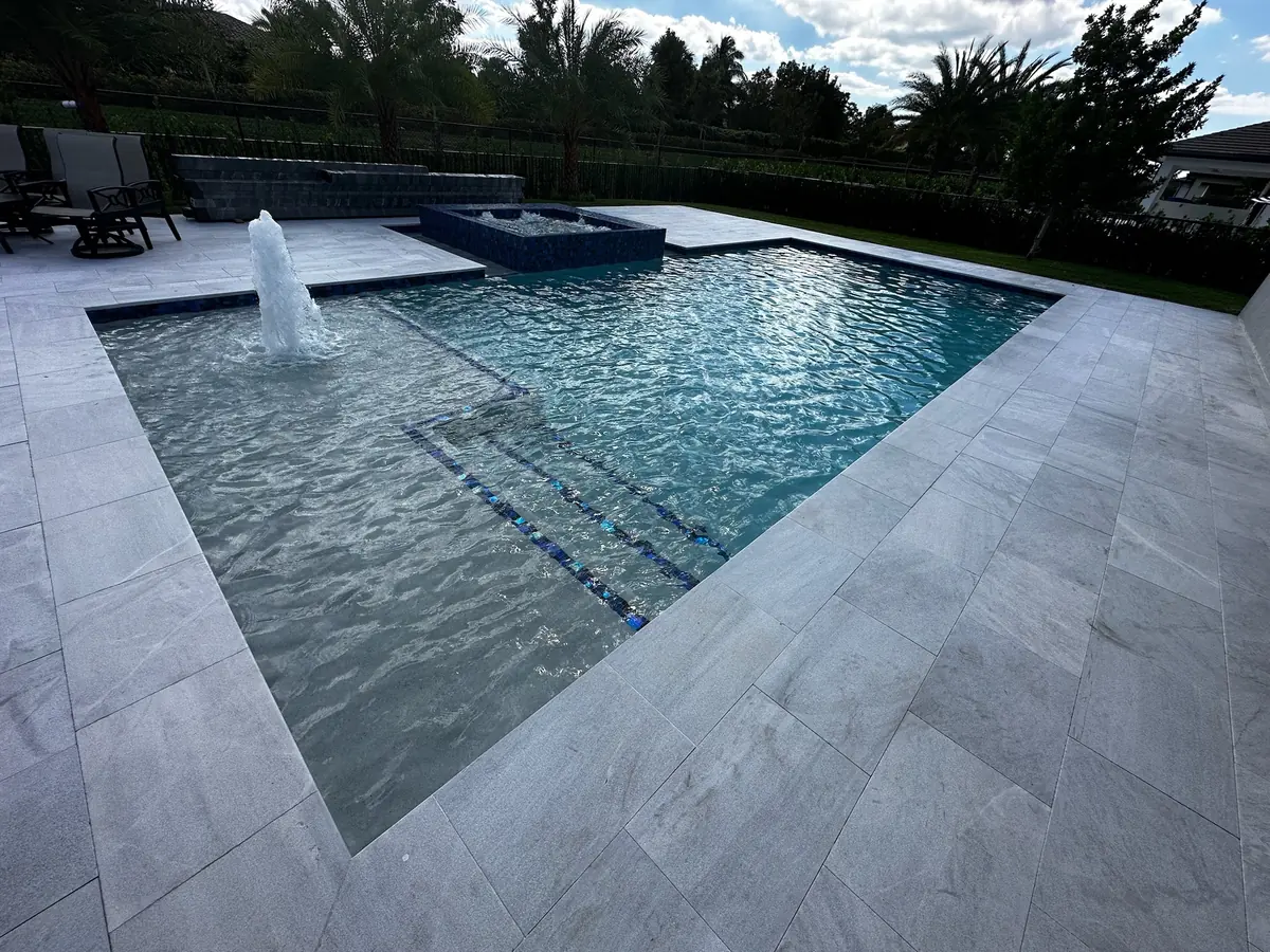 Pool and tanning ledge with a water jet, mosaic spa and sparkling water in warm light
