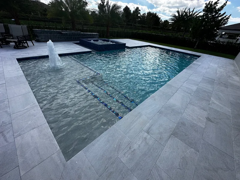 Pool and tanning ledge with a water jet, mosaic spa and sparkling water in warm light