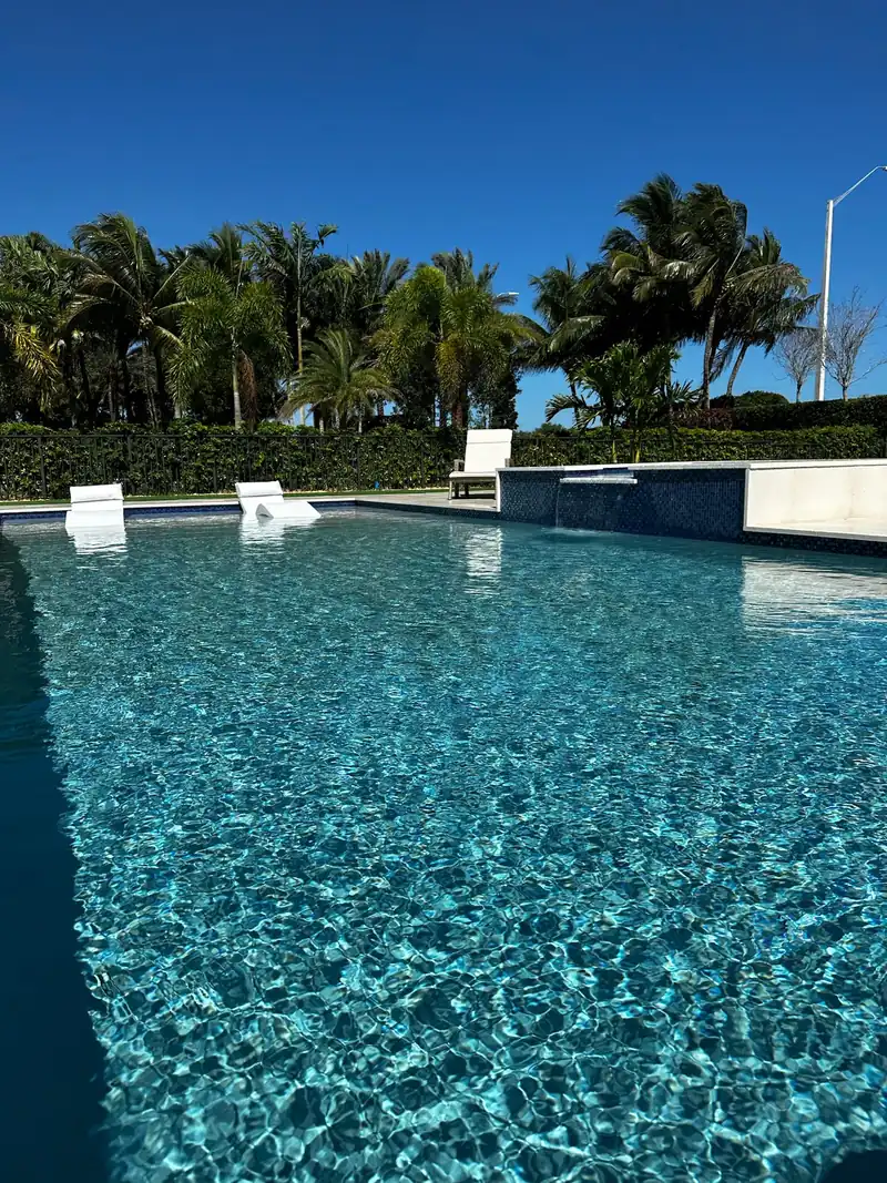 Sparkling turquoise pool water with white loungers and a raised spa in the distance